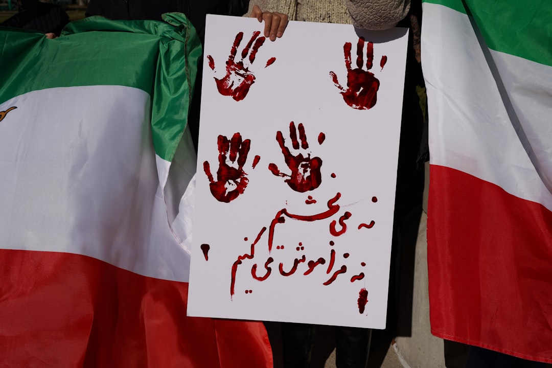 Protestors hold sign with bloody handprints and persian text.